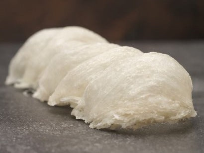 Three cleaned white bird's nests, cup-shaped and translucent, resting on stone.
