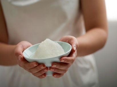 Two hands holding a small porcelain bowl of cleaned white bird's nest.